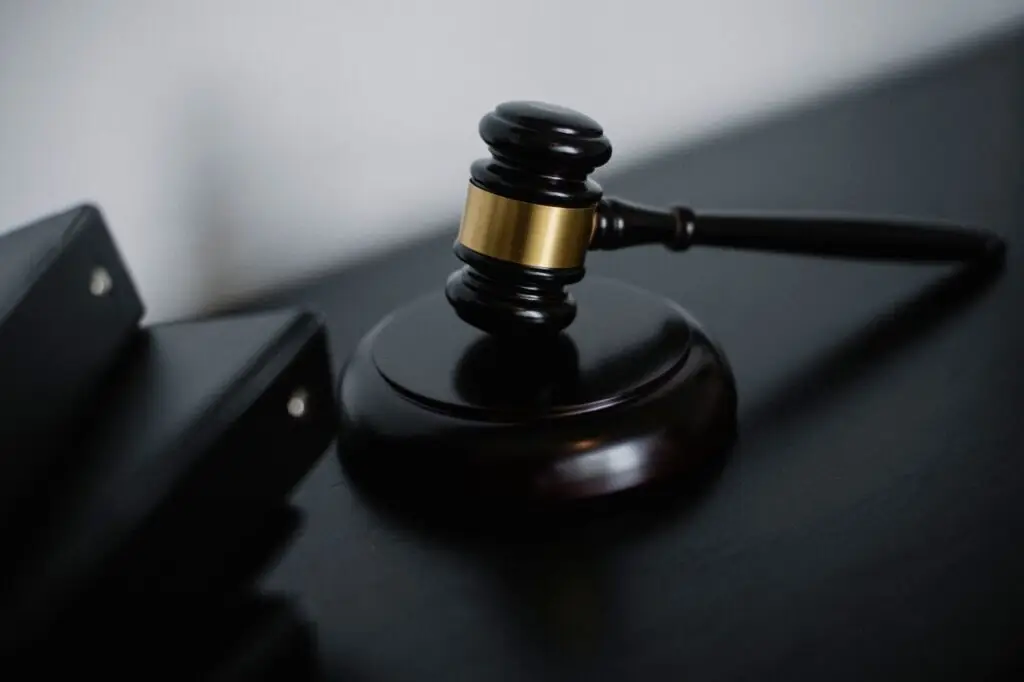 High angle of shiny wooden ceremonial mallet with golden detail placed on judge tale near documents folders